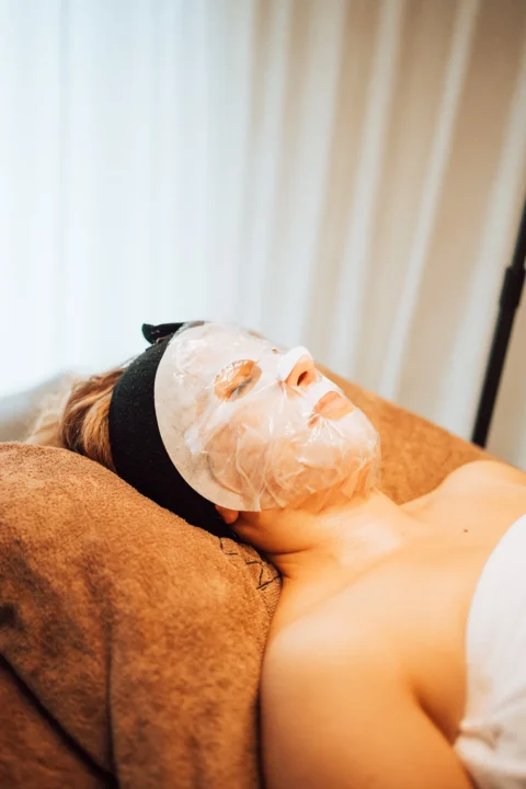 Klant ontspant met een verzorgend masker op het gezicht tijdens een behandeling