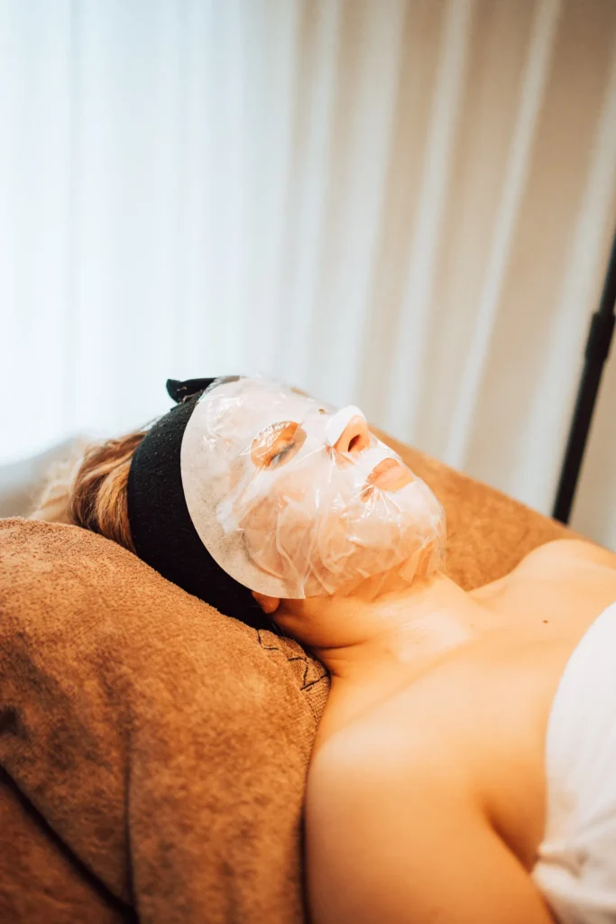 Klant ontspant met een verzorgend masker op het gezicht tijdens een behandeling
