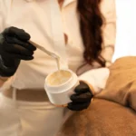Marin neemt met een spatel verzorgende creme uit een potje voor een gelaatsbehandeling