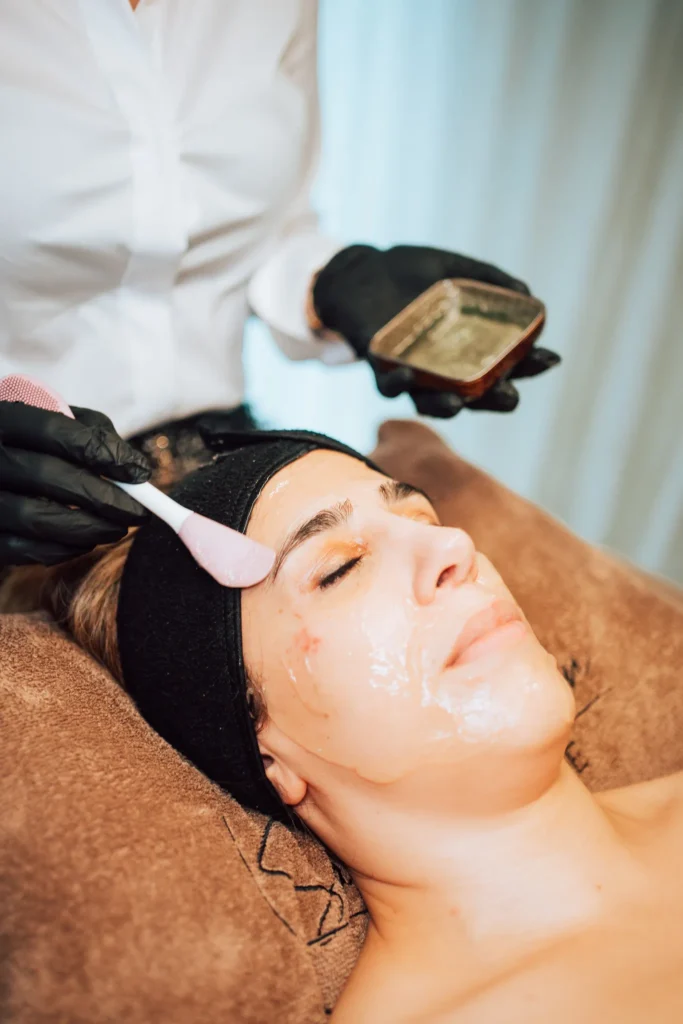 Een masker wordt met een penseel op het gezicht aangebracht tijdens een gelaatsbehandeling