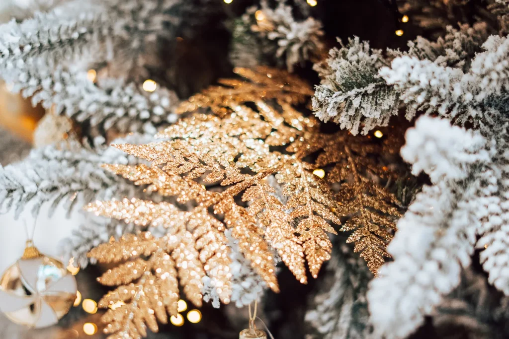 Besneeuwde takken met een gouden varenblad en warme lichtjes