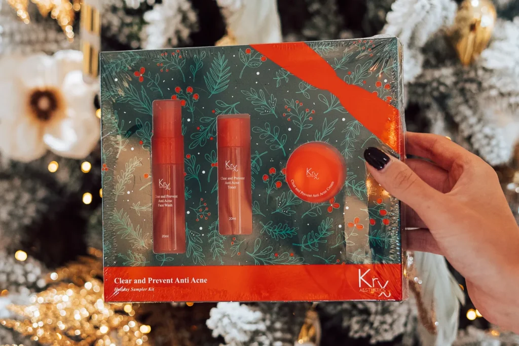 Hand houdt de KRX Clear and Prevent Anti Acne-set vast, met twee flesjes en een potje